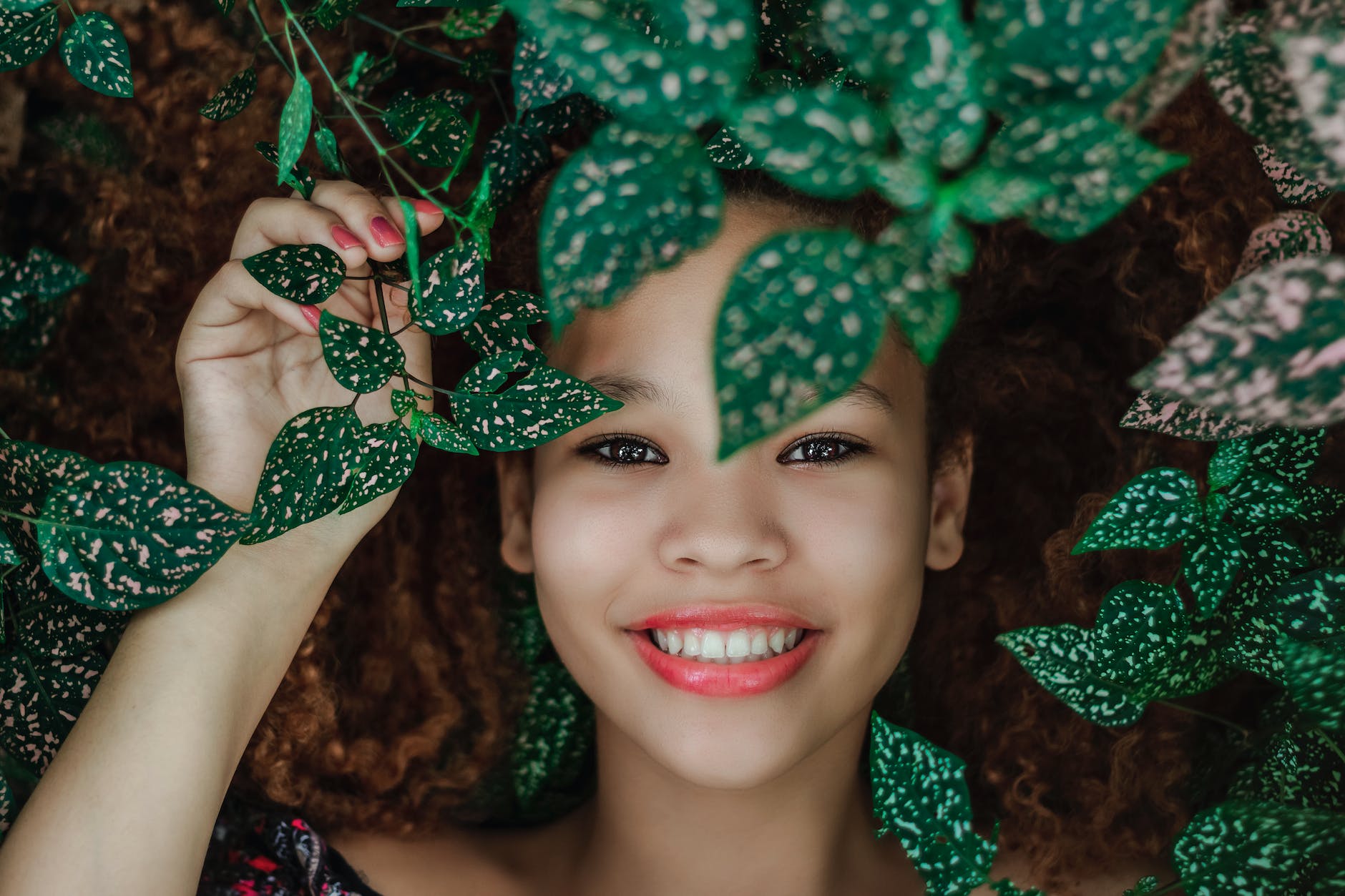 photo of woman smiling near leaves